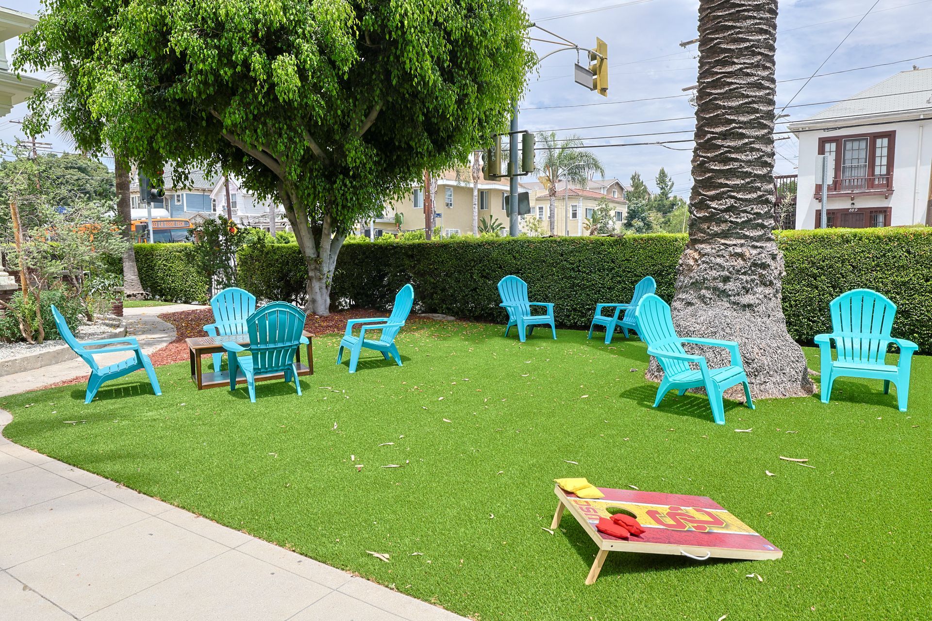 This image showing a spacious courtyard with 8 zink colour chairs and with some painting stuff in it.