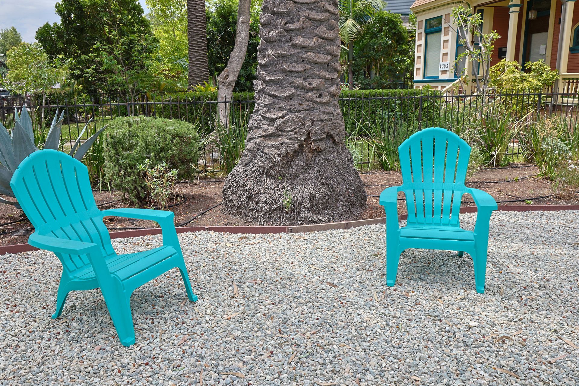 This image showing date tree with two zink colour chairs in it.