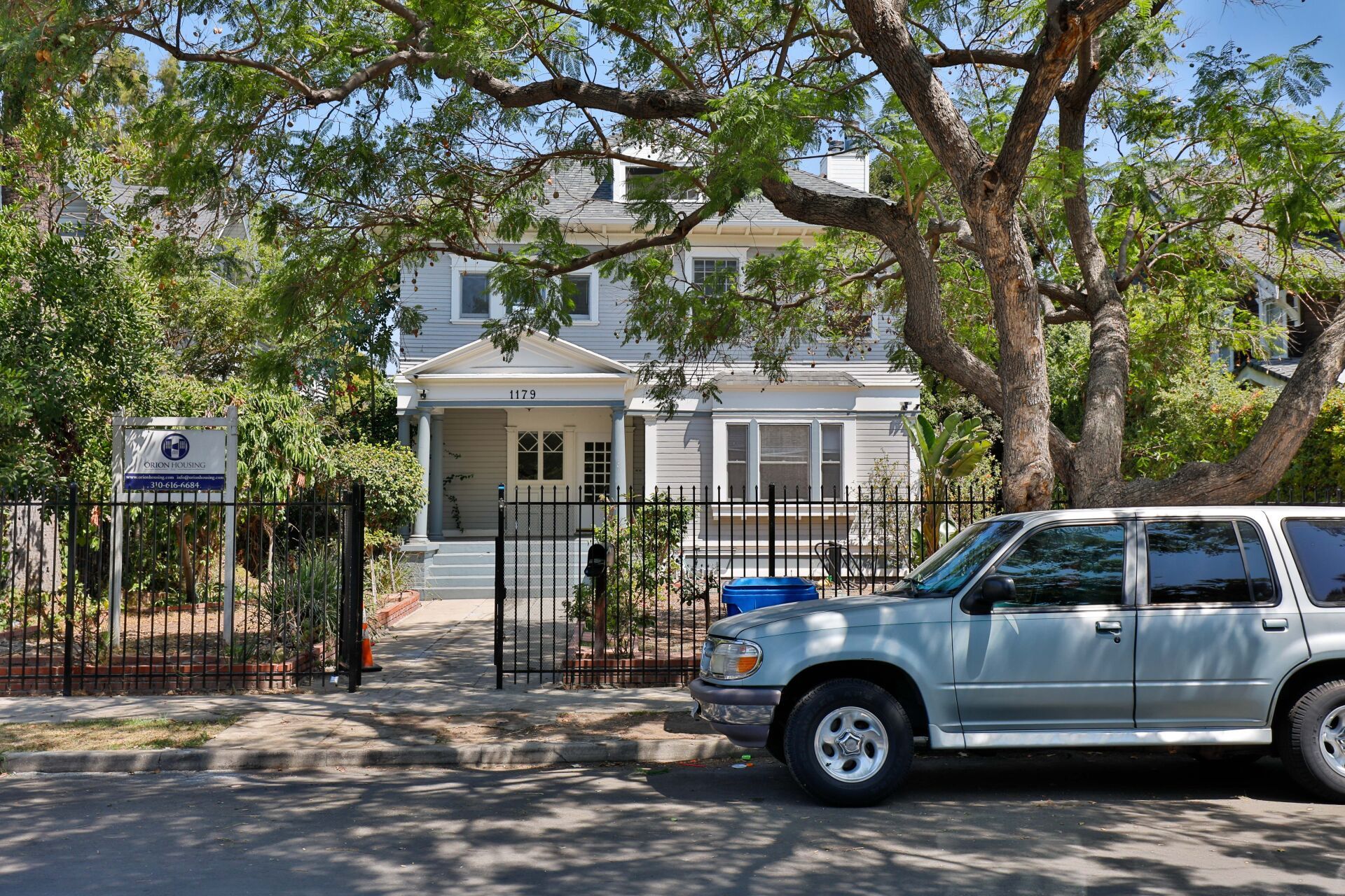 This image shows a car is standing on the road and a tree or house is also there