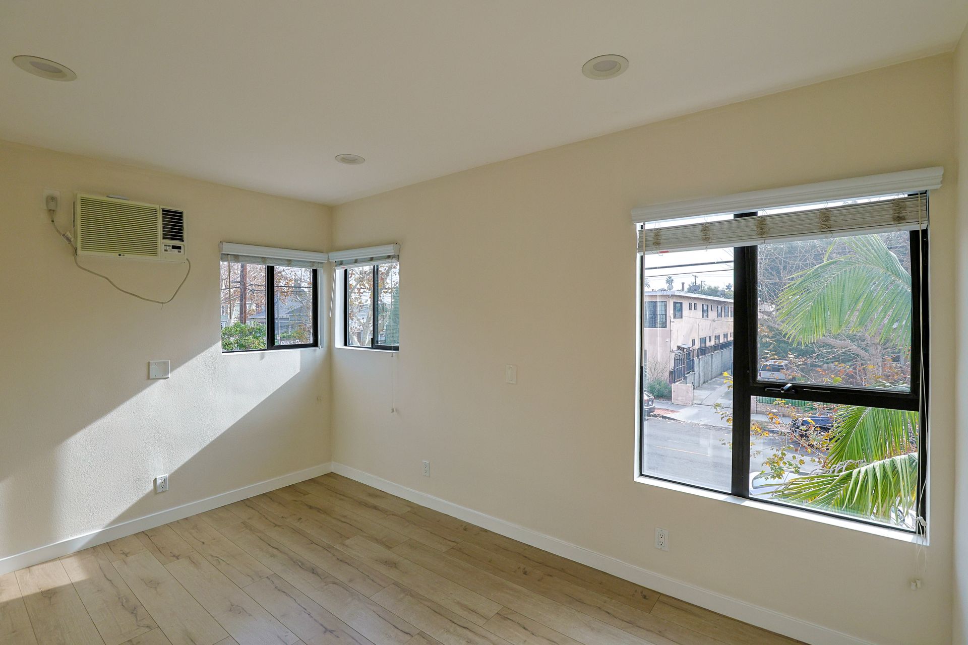 This image showinf a spacious blank room with two windows in it.