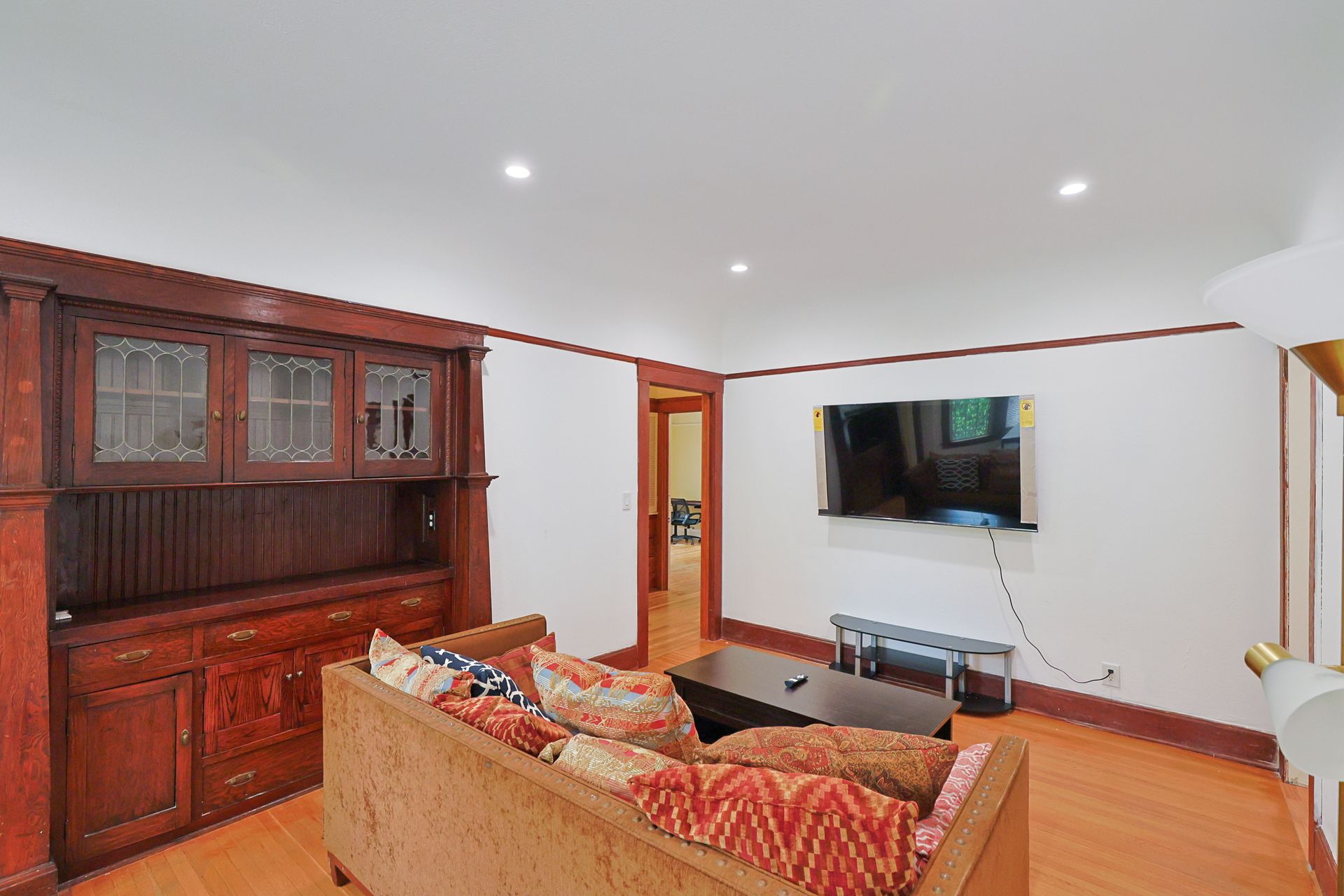This image showing a spacious living room with furniture and smart tv.