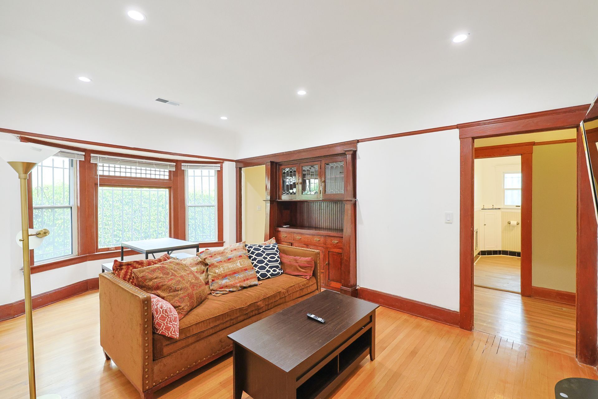 This image showing a spacious living room with cough and furniture and windows in it.