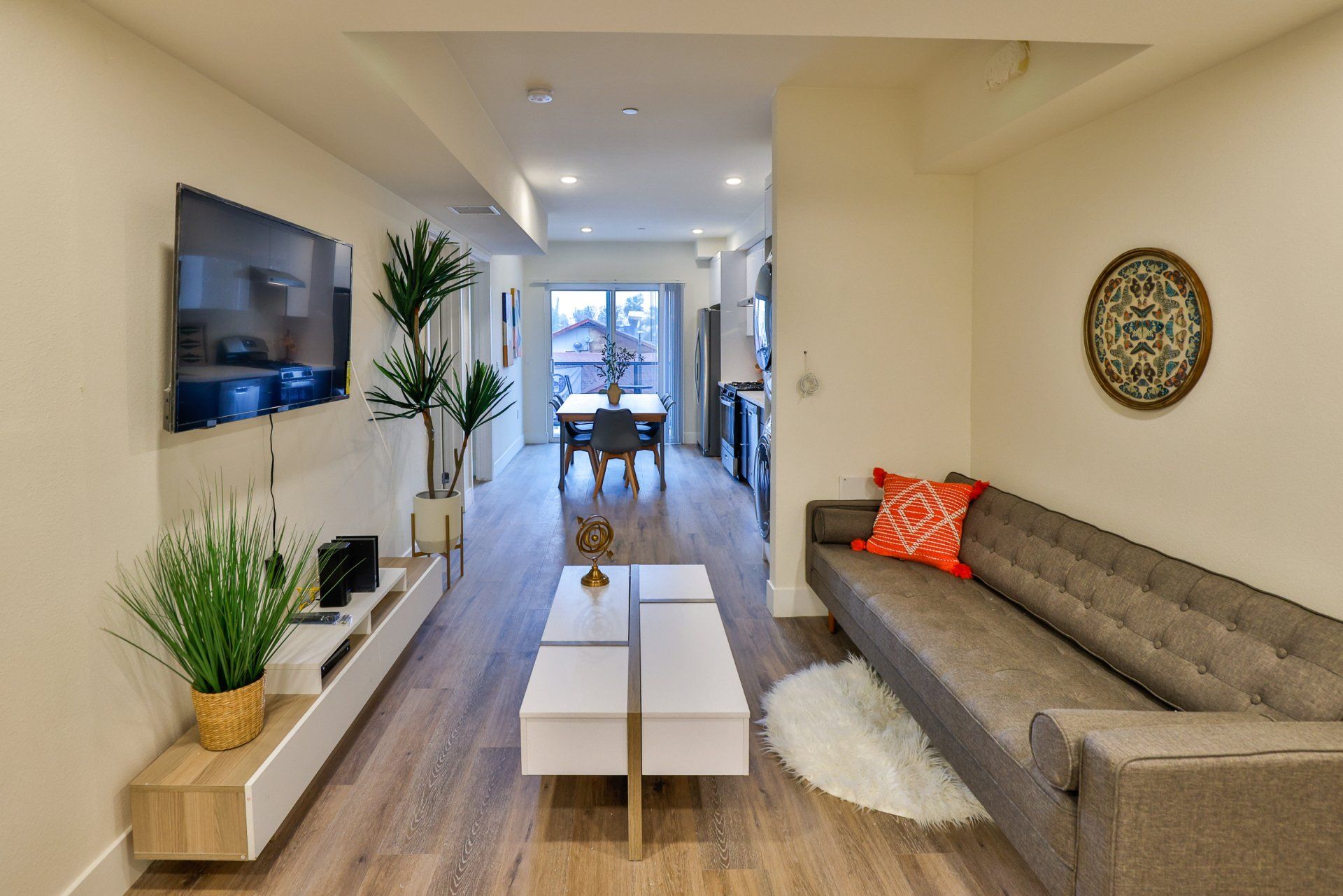 This is the image of a living room with brown sofa, white table, LCD and more