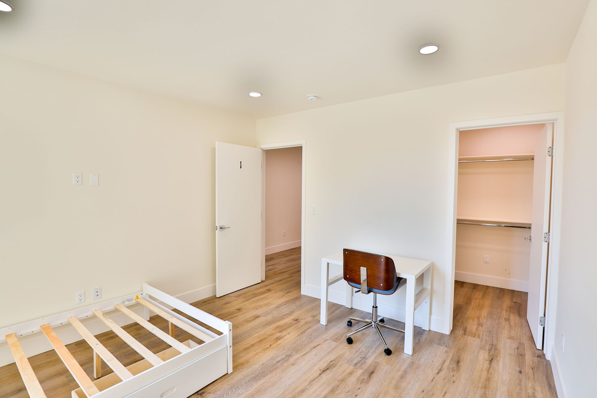 This image shows a room with a desk , brown chair  and bed.