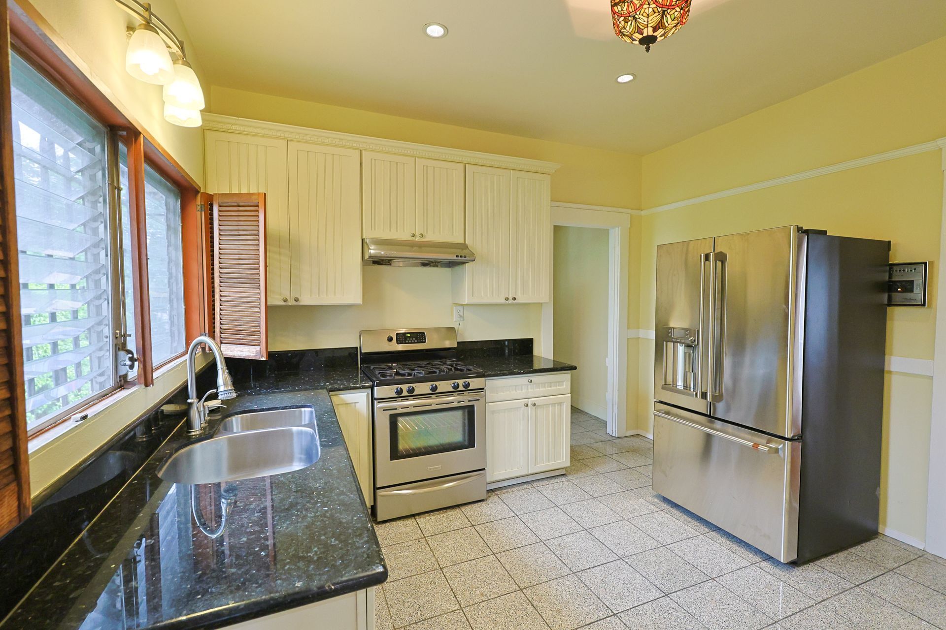 This image shows the kitchen with yellow background and brown window borders