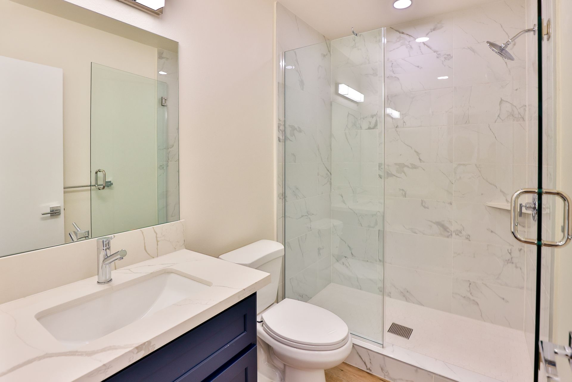This image showing a bathroom with white walls, two mirrors, one commode seat and sink in royal blue colour.