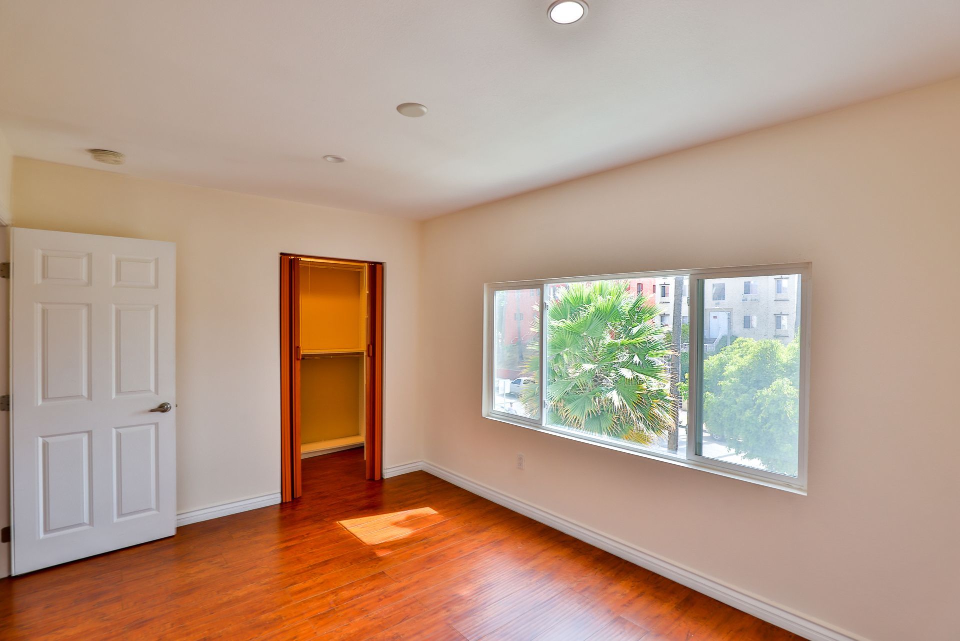 This image showing a blank room with windos, one small cupboard in it.