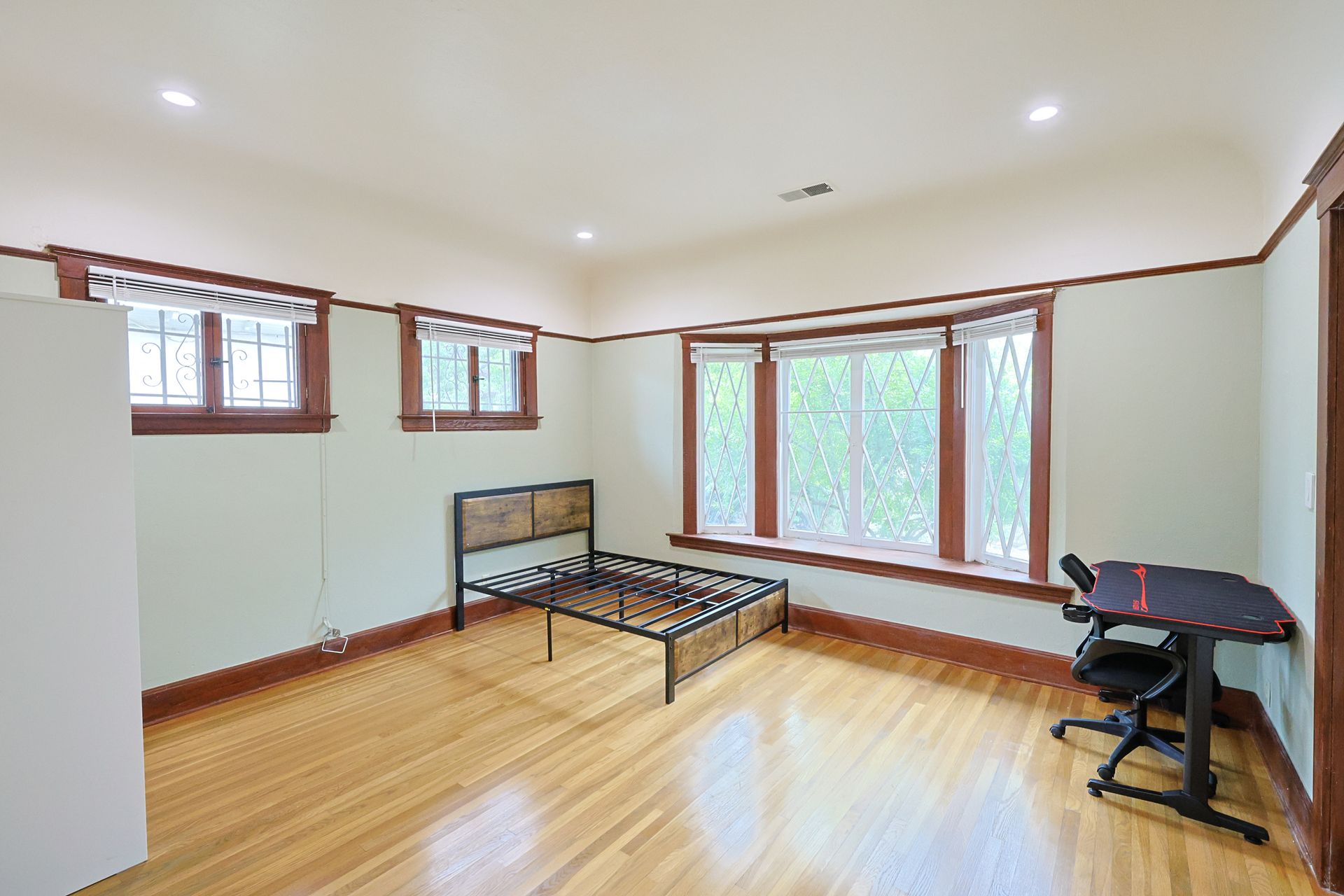 This image showing a spacious with gaming table, a single bed chair and lots of windows in it.