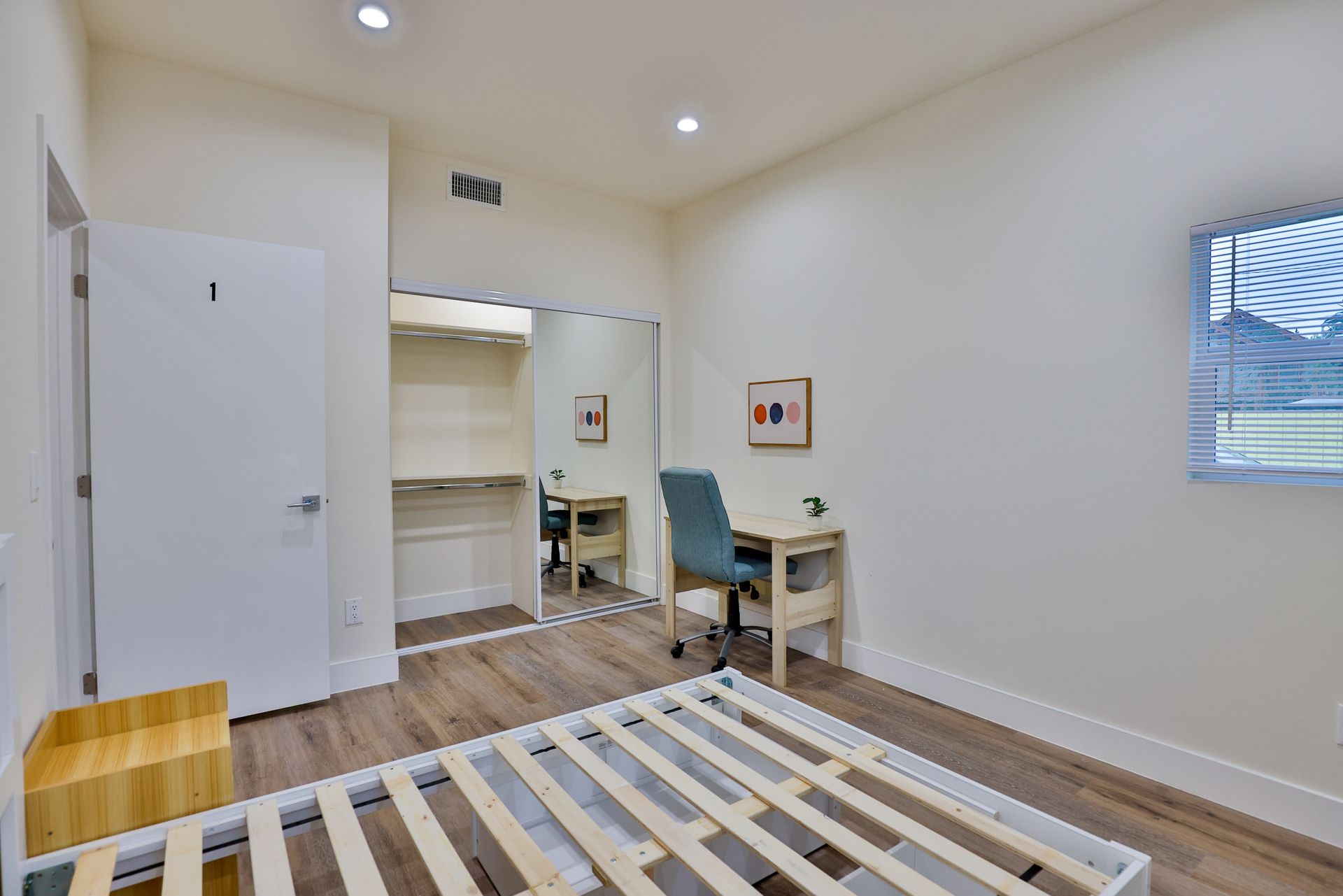 This image showing a white bedroom with  one window, cupboards and furniture in it.