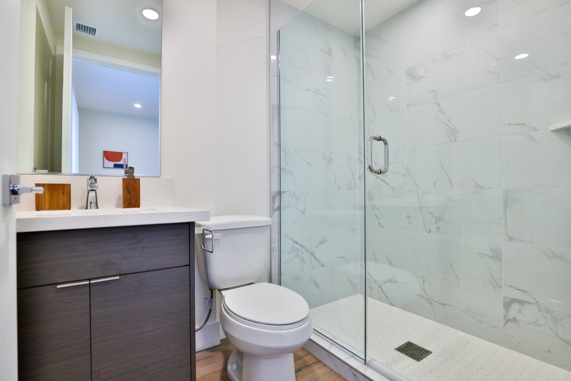 This image shows a bathroom with a glass shower and toilet.