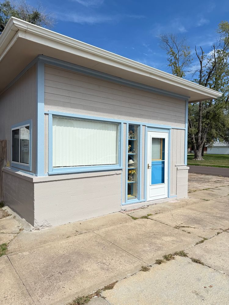 Small tan storefront with blue trim and awning, seen from outside on a sunny day