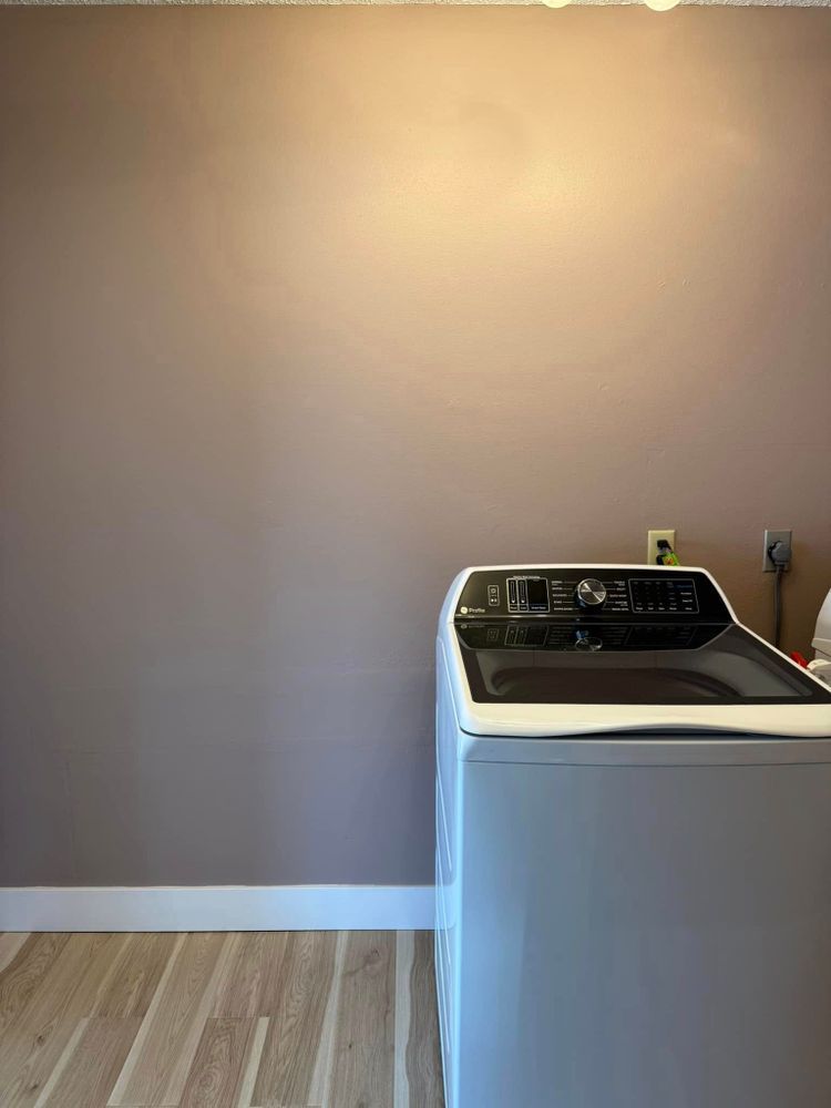 Laundry room with beige walls, wood floor, and a white washer against the wall