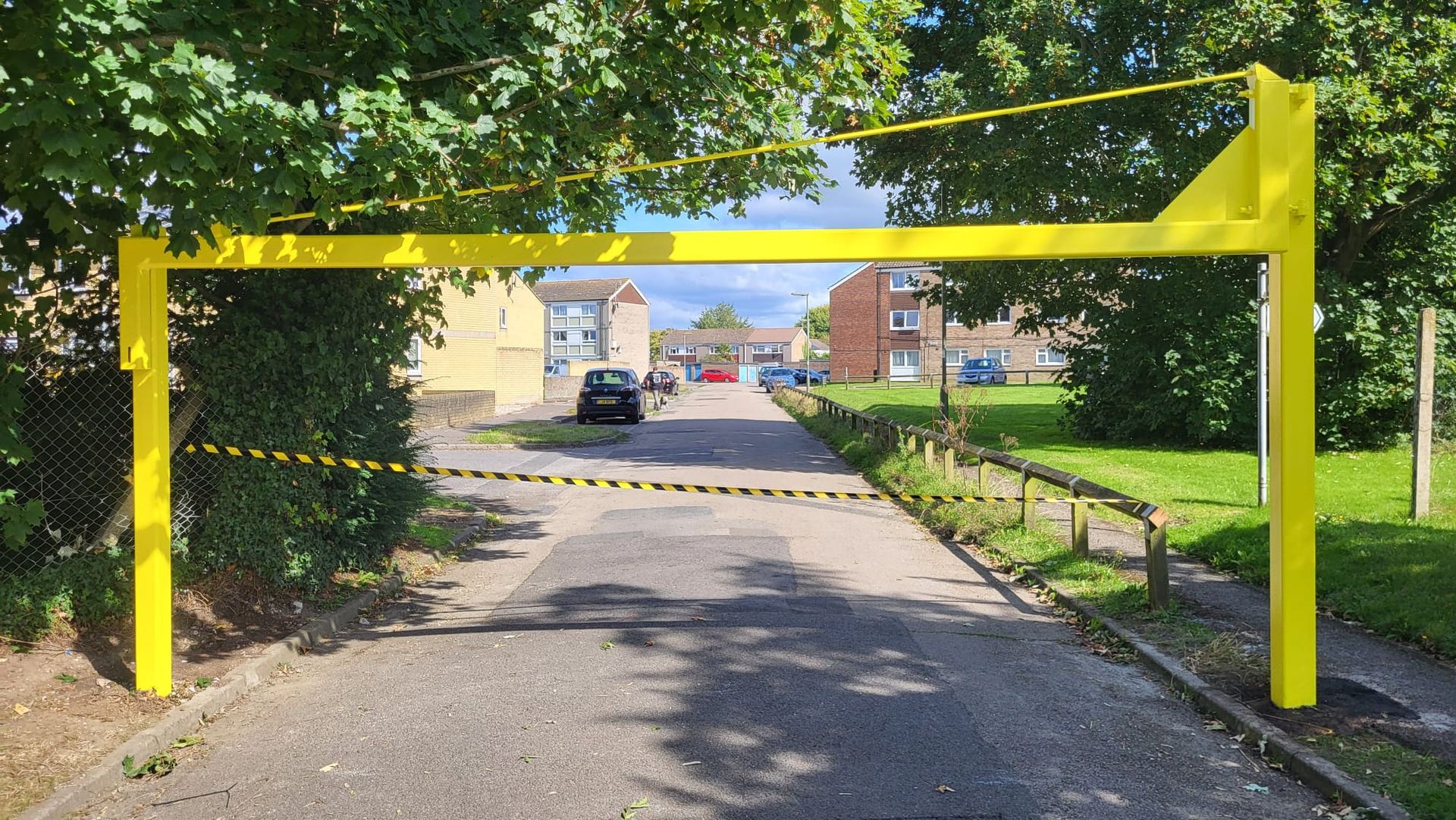 A yellow gate is blocking a road in a residential area.