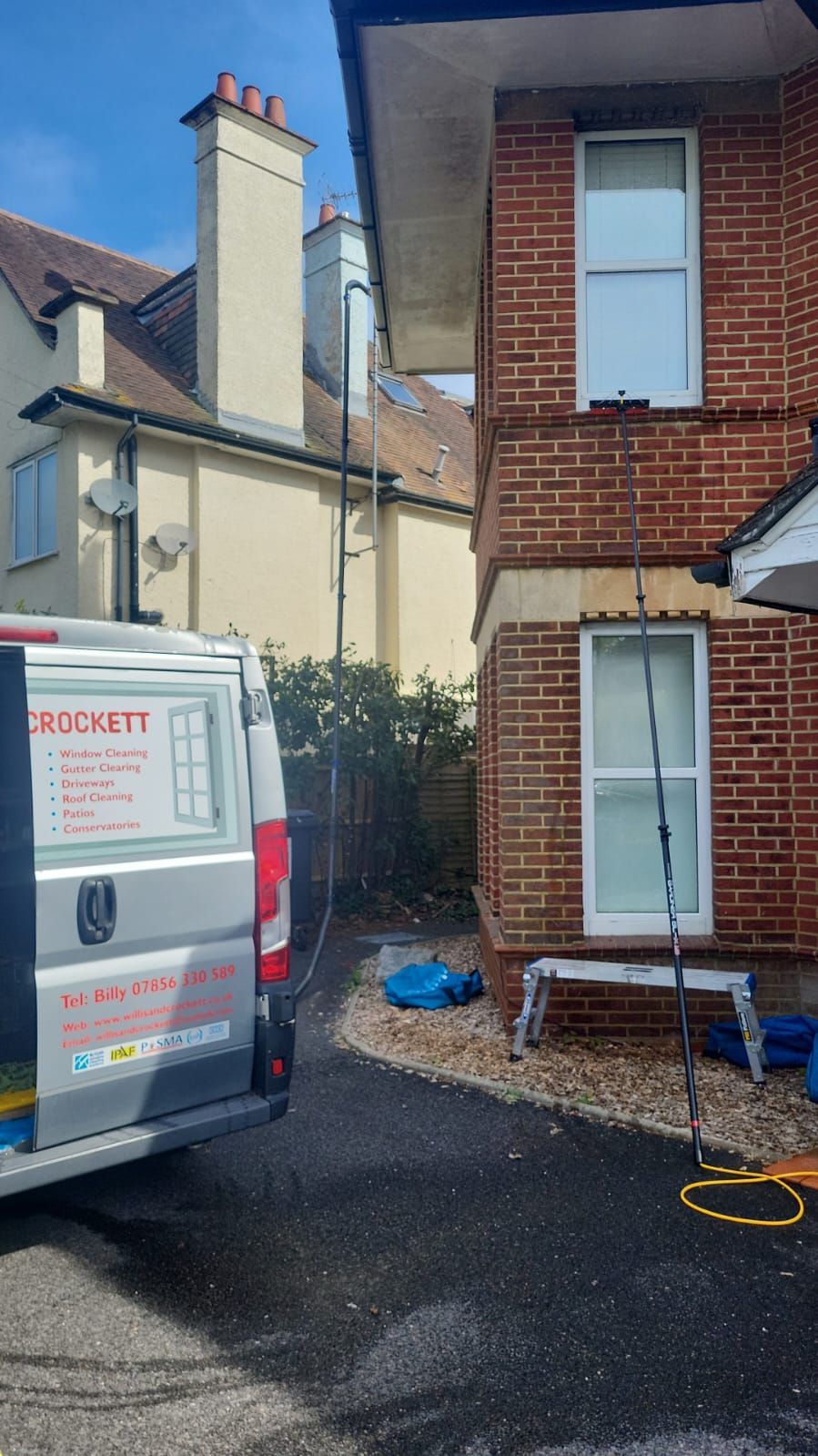 A van is parked in front of a brick house which is being cleaned
