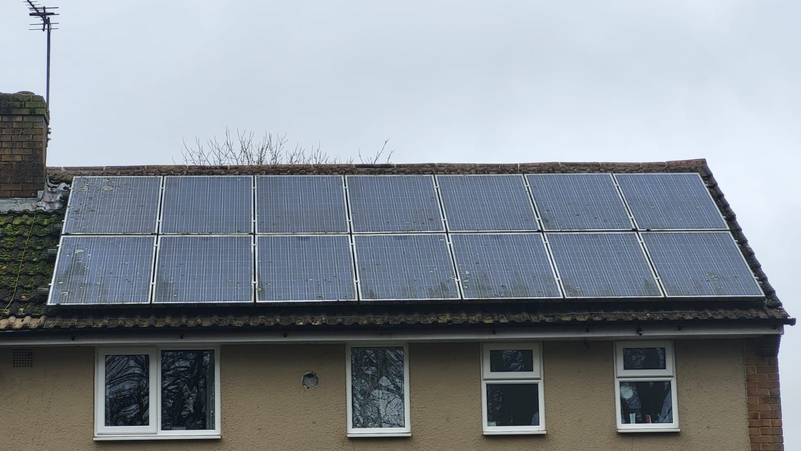 A house with a lot of dirty solar panels on the roof