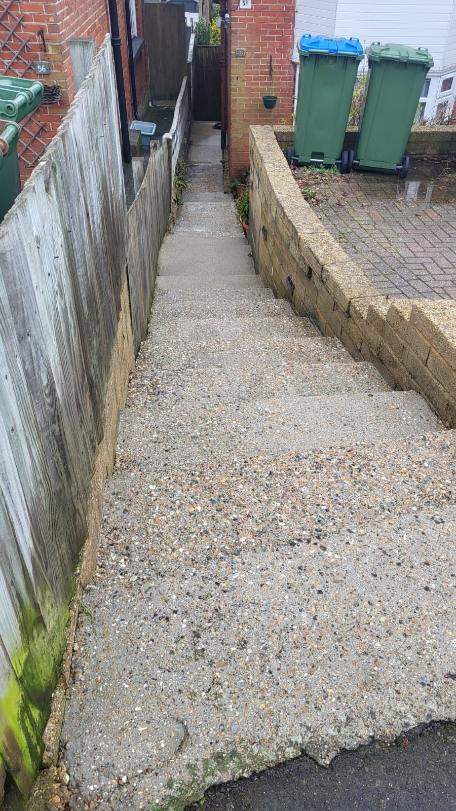 A set of stairs leading up to a house next to a fence.