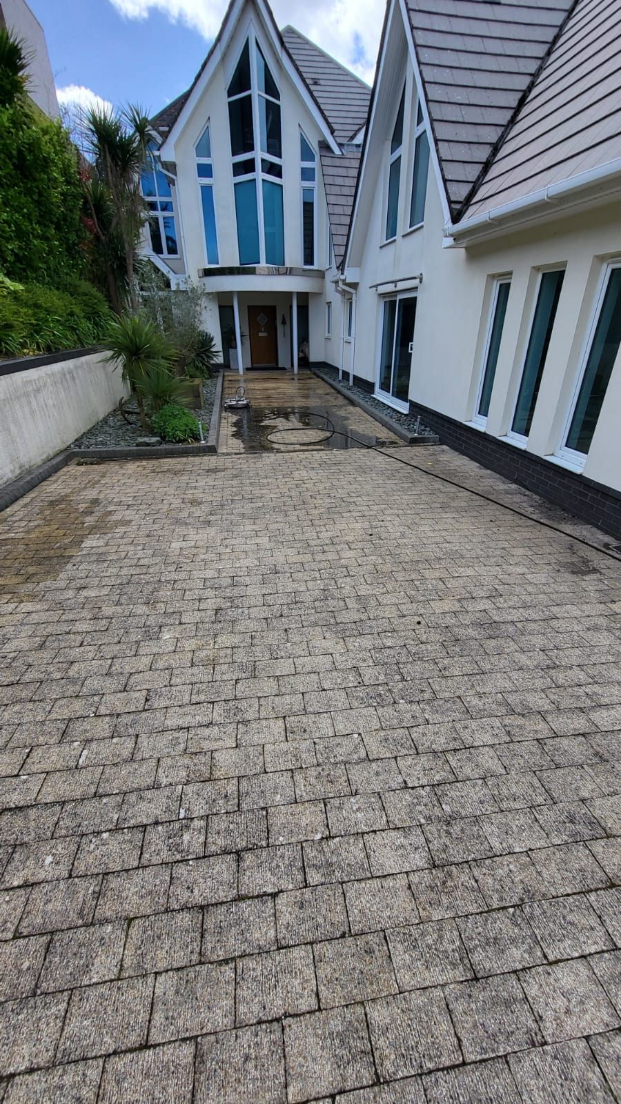 A large white house with a dirty brick driveway leading to it.