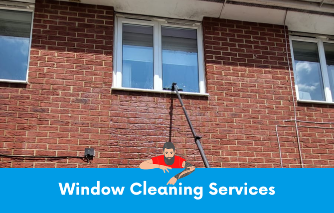 A man is cleaning a window on the side of a brick building.