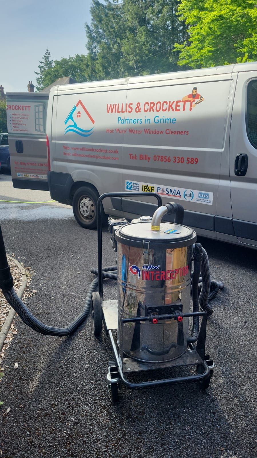 A vacuum cleaner is sitting on a cart next to a van.