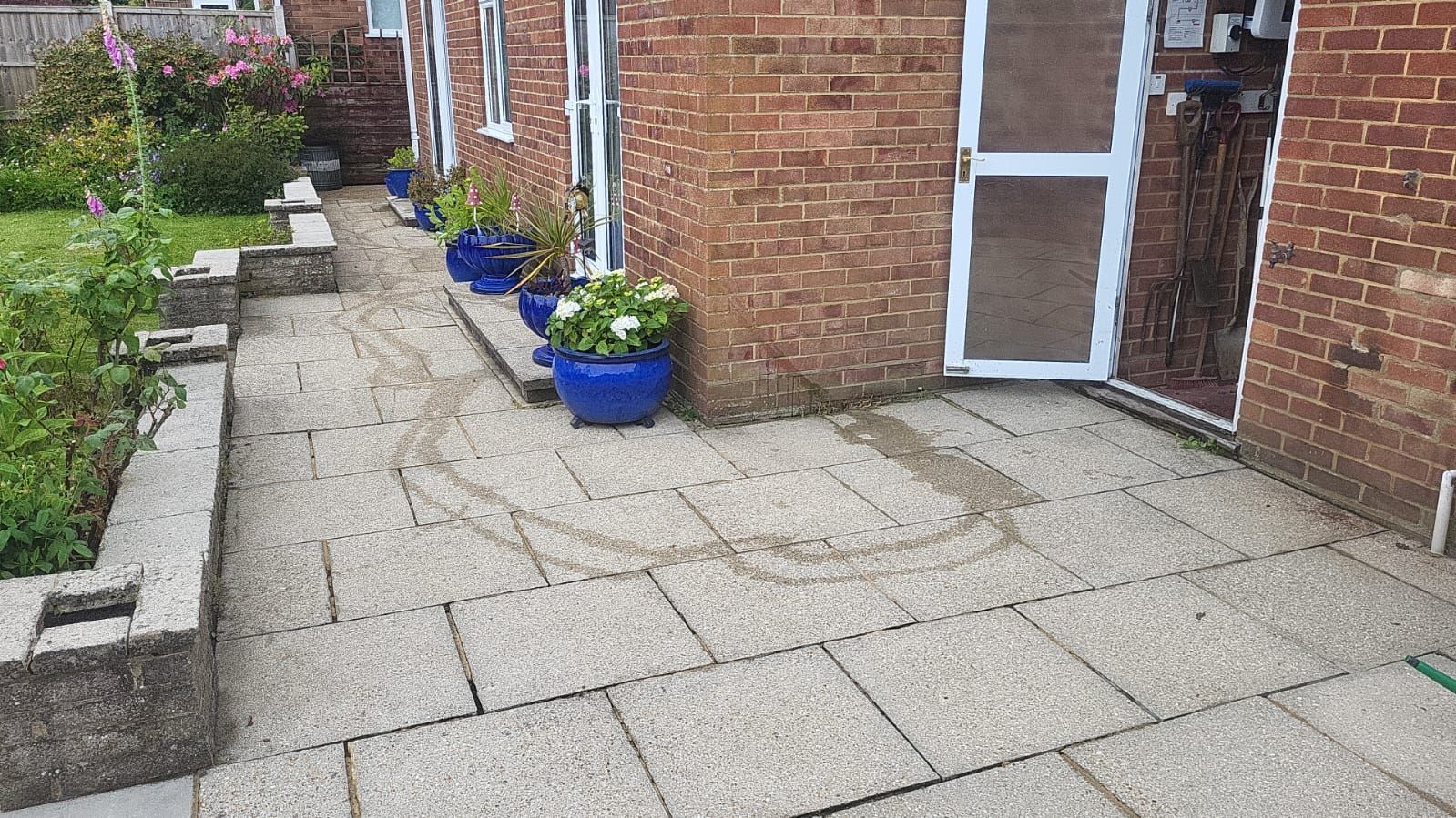 A brick house with a patio and blue potted plants in front of it.
