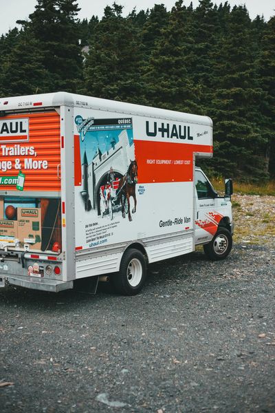 A white and red u-haul truck is parked in a gravel lot.