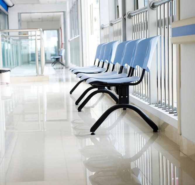 Blue chairs in a bright, empty hallway, likely a waiting area.