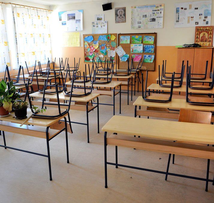 Empty classroom with desks, chairs stacked, and bulletin boards.