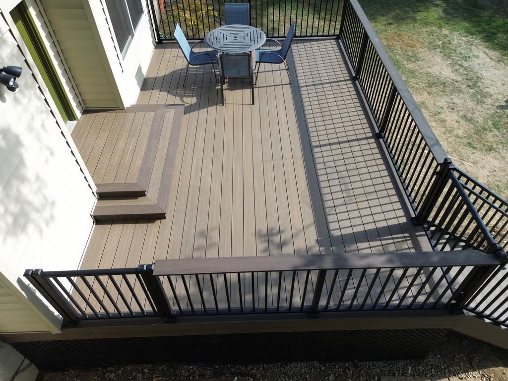 Elevated deck with composite boards, black railing, and outdoor furniture.