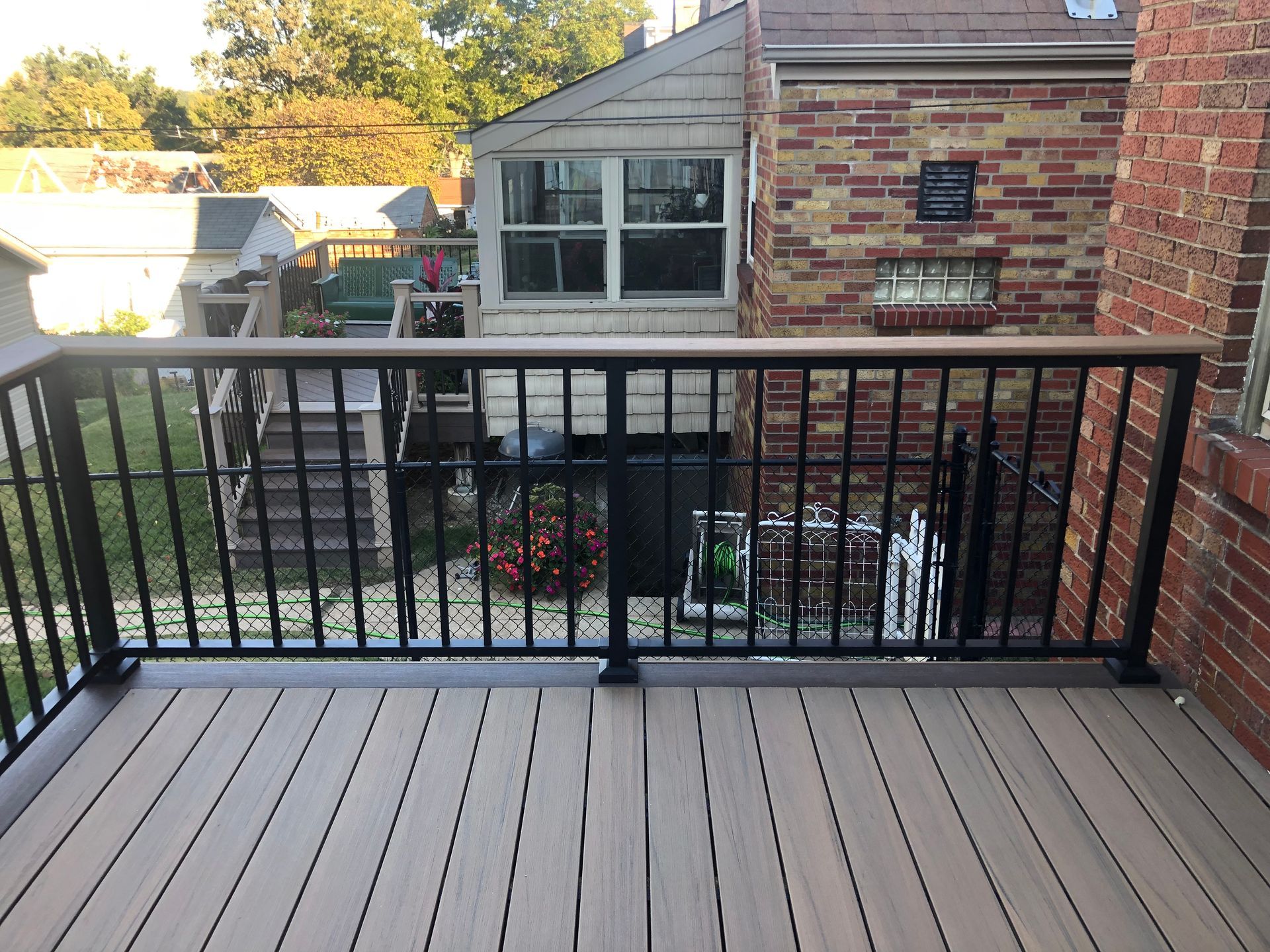 Deck with black railing, brown composite decking, and a view of a backyard.