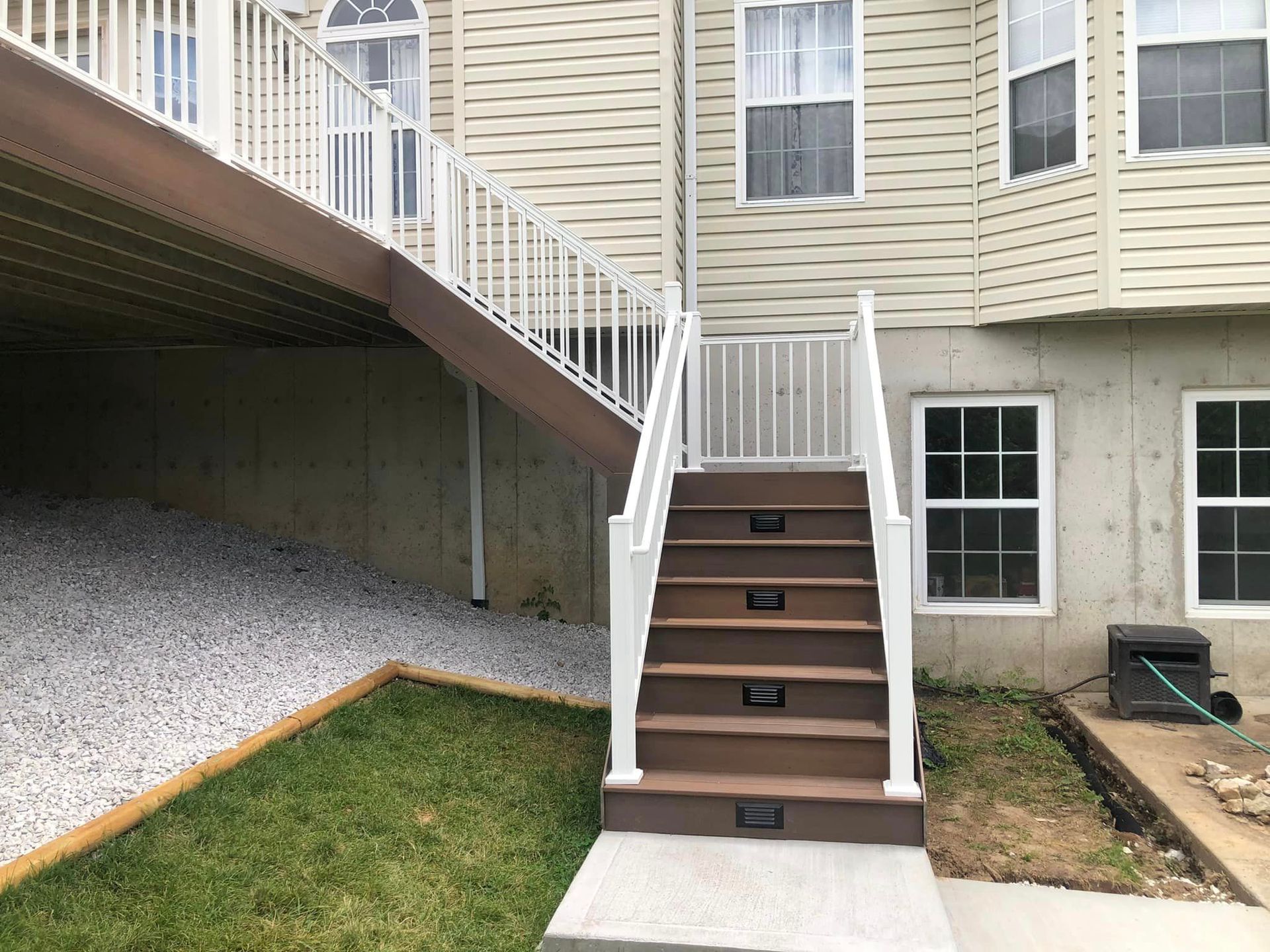 Exterior staircase leading from deck to ground level, with built-in lights and white railing.