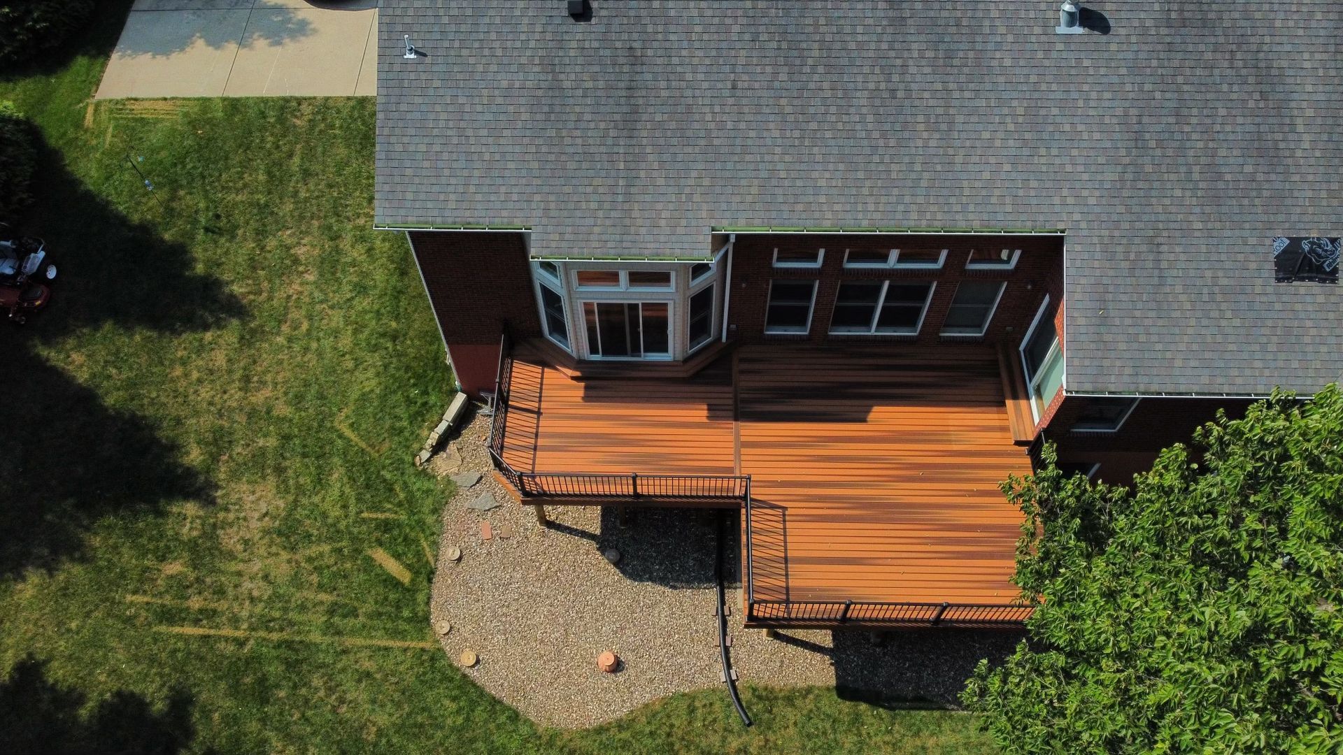 Aerial view of a house with a multi-level wooden deck and a rounded bay window.