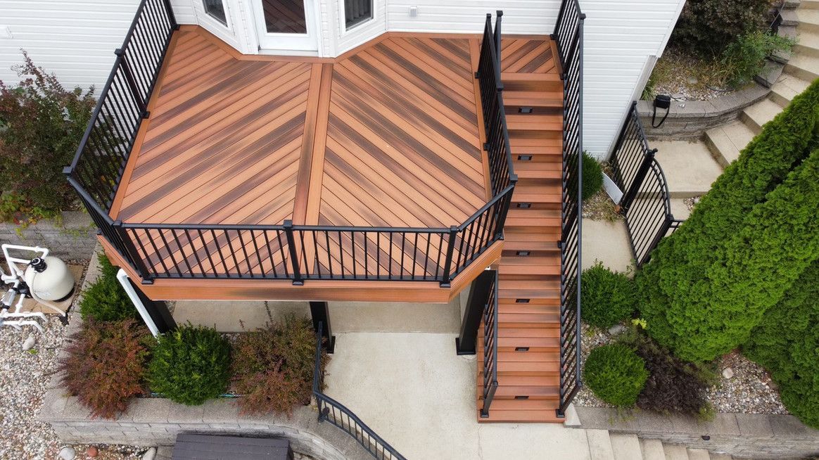Wooden deck with stairs, black railing, and chevron pattern.