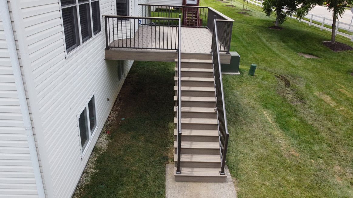 Exterior shot of a white house with a deck and stairs leading down to a grassy yard.