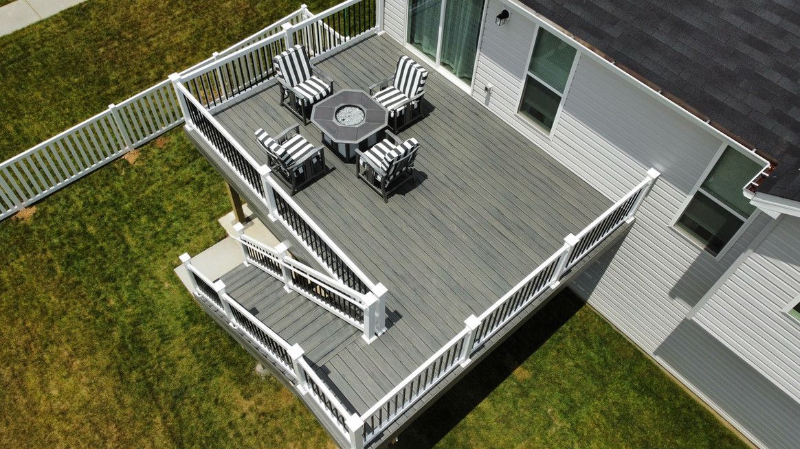 Elevated gray deck with white railings, stairs, and outdoor seating.