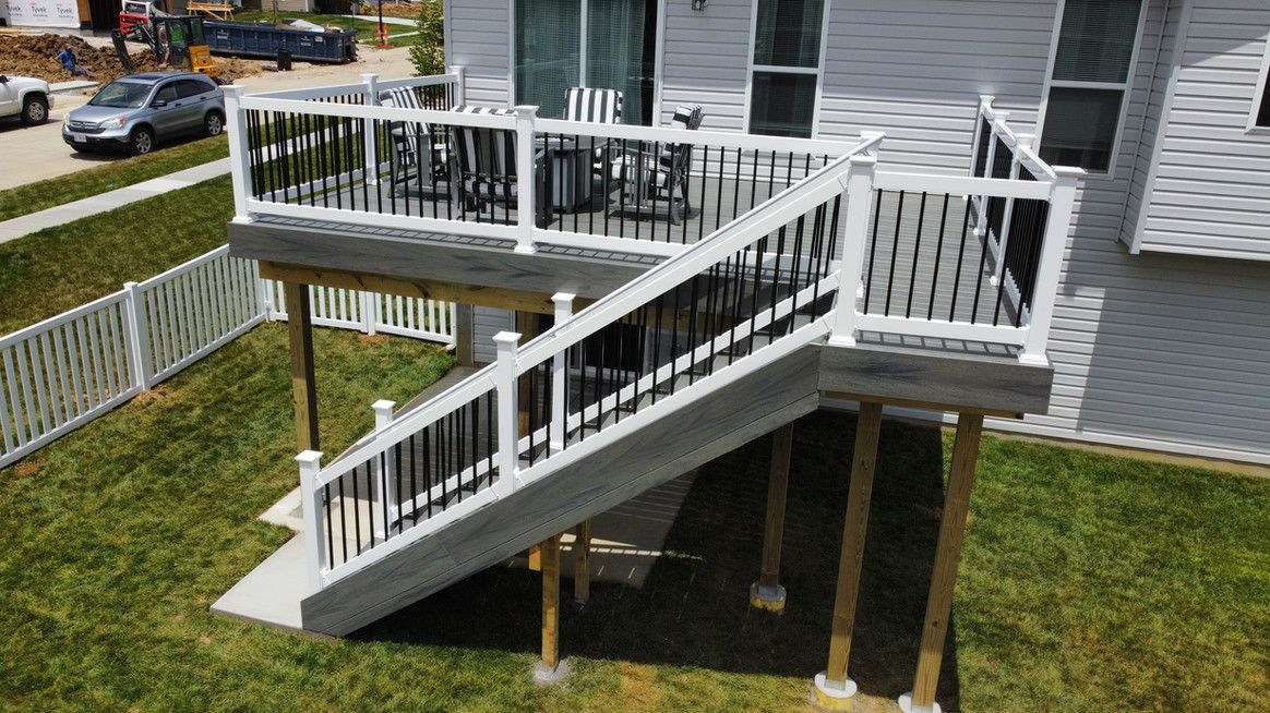 Deck with white railing and black balusters; stairs lead down to a grassy yard.