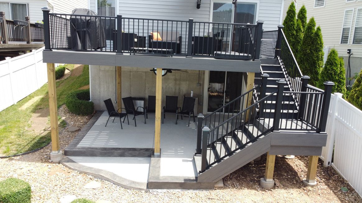 Multi-level deck with black railing and stairs, gray decking, and seating area below.