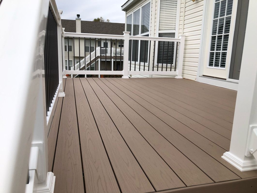 Brown composite deck with white railings, view of a house and another deck.