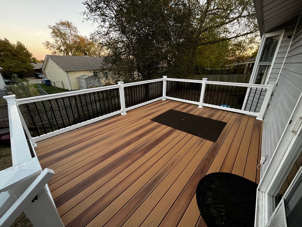 Wooden deck with black railings and white posts; a black mat sits in the center.