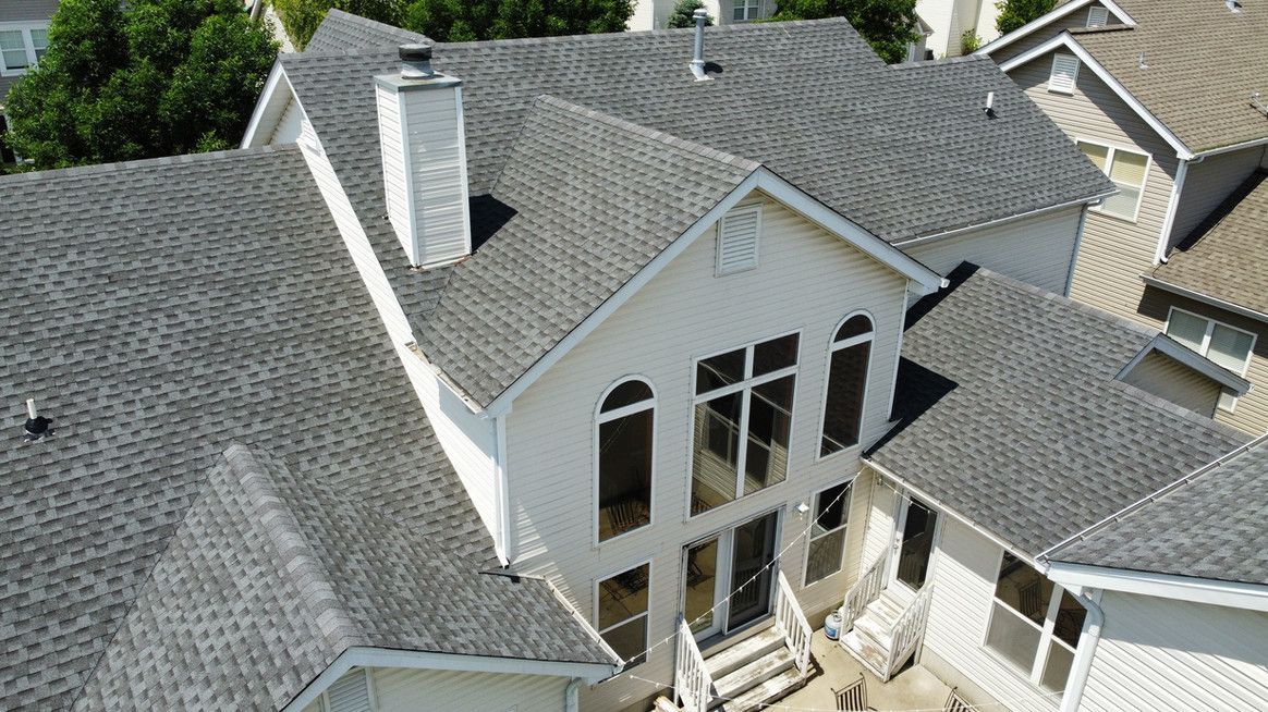 Overhead view of a white house with gray shingle roof and chimney.