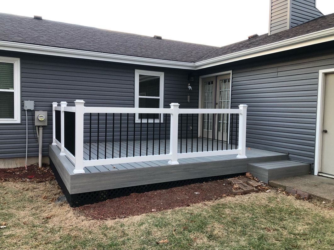 Gray deck with white railing, black spindles, and a gray house.