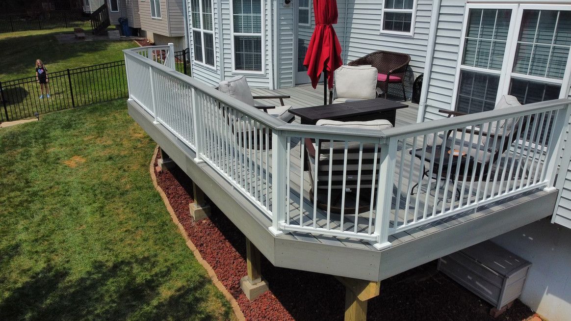 Deck with white railing and outdoor furniture. A red umbrella provides shade.