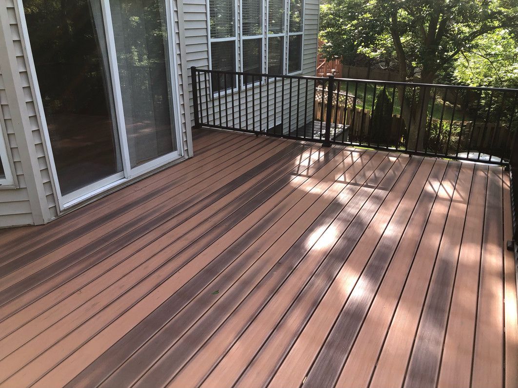Composite deck with brown and gray boards, black railing, and sliding glass door.