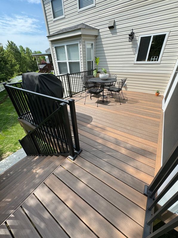 Composite deck with black railing, table and chairs. A grill sits under a cover on the deck.