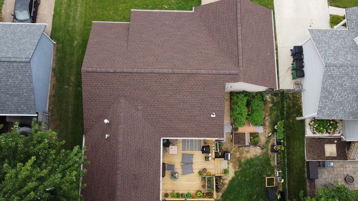 Overhead view of a house with a brown roof, deck, and a small garden.