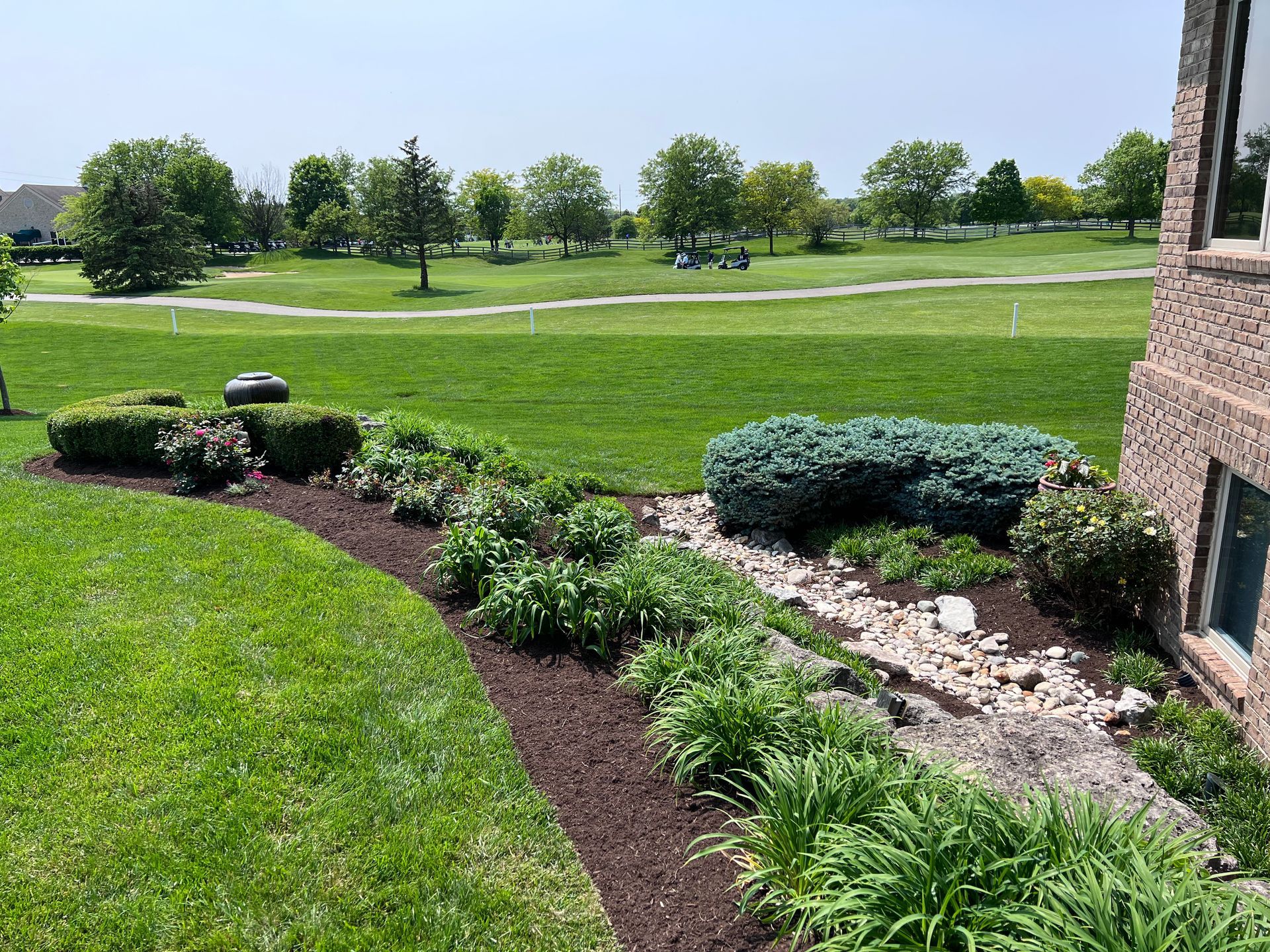 A person is mowing a lush green lawn with a lawn mower.