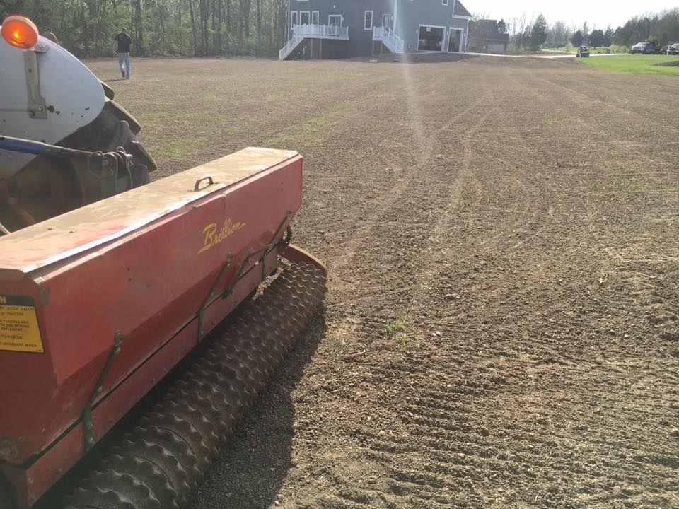 A tractor is plowing a field with a planter in the foreground