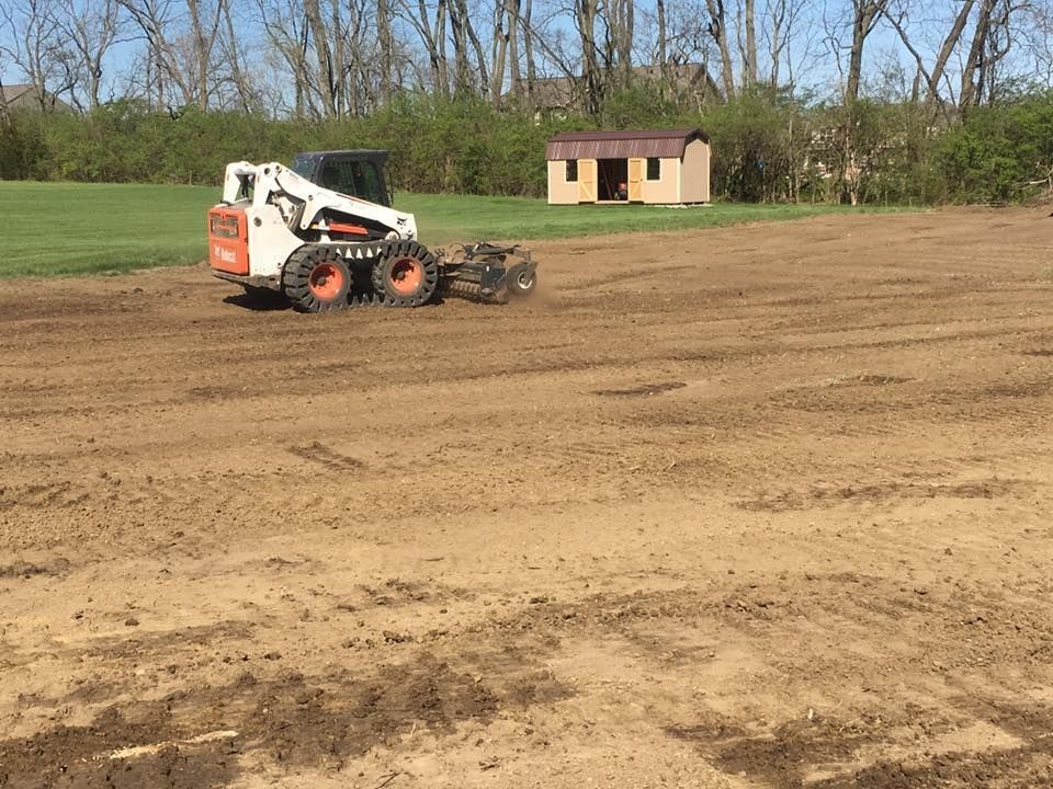 A bobcat is moving dirt in a field.