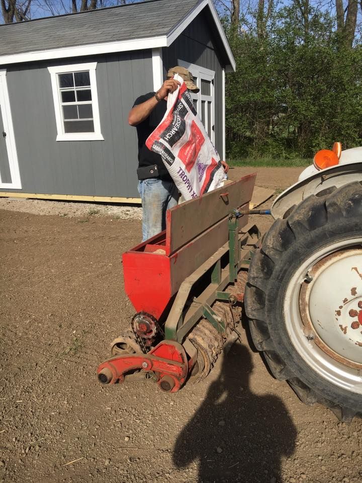 A man is standing next to a tractor holding a bag of fertilizer
