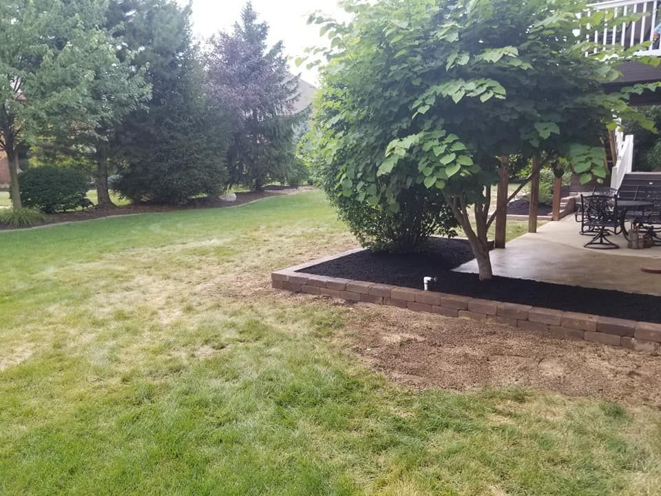 A backyard with a patio and a tree in the middle of it.
