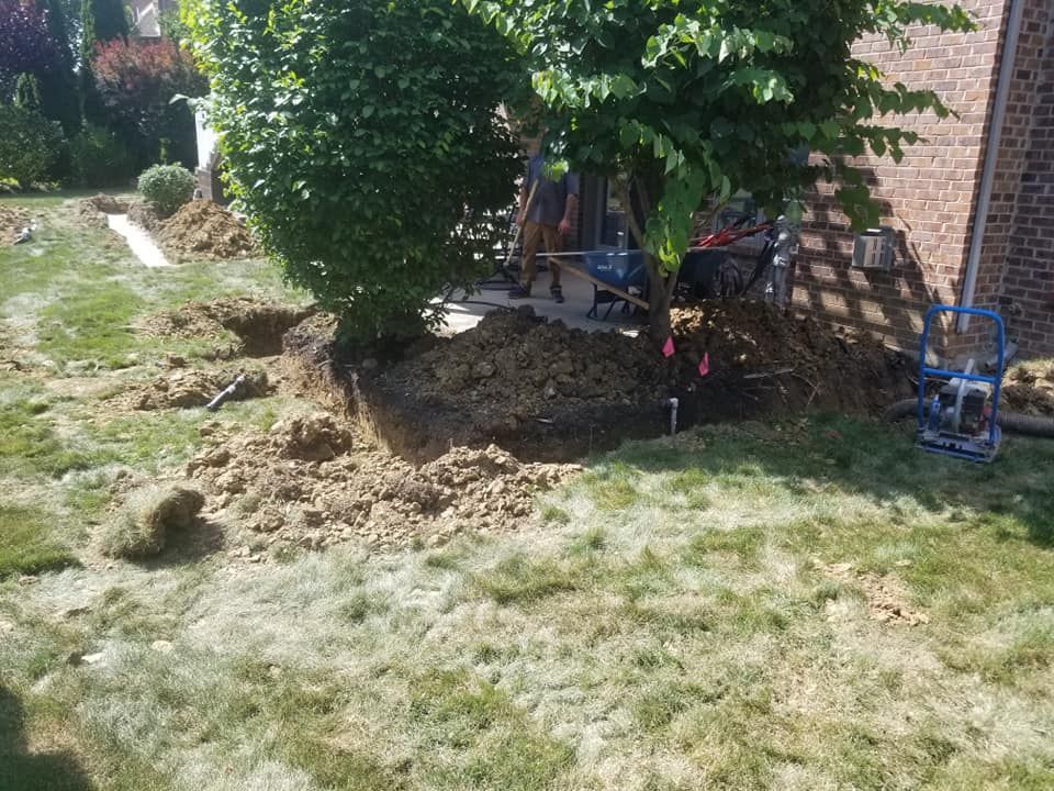 A man is digging a hole in the ground in front of a house.